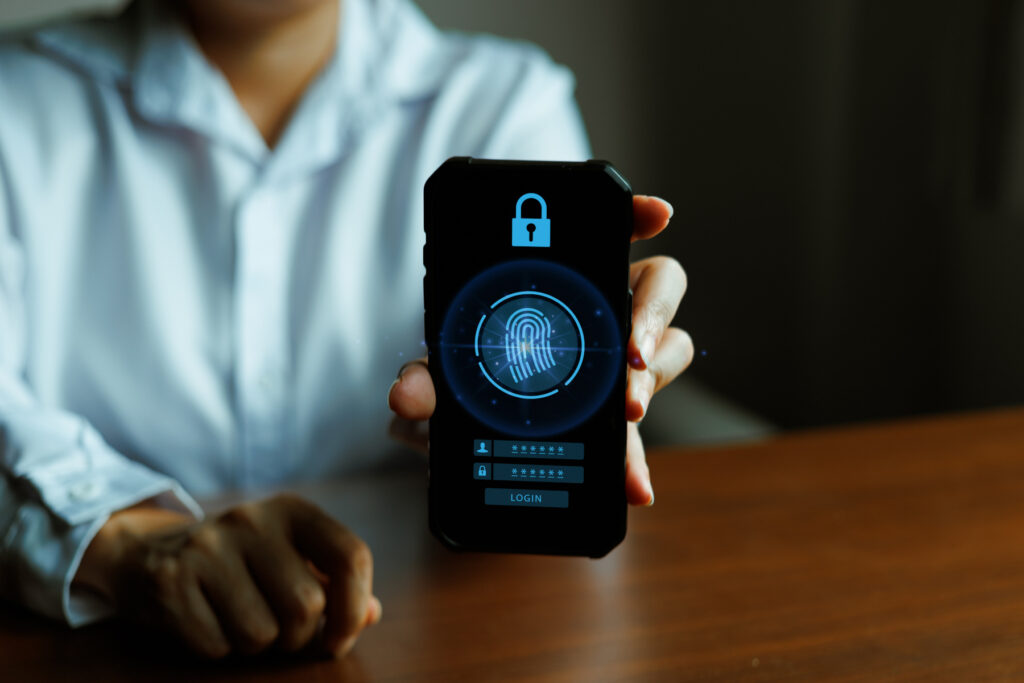 Hand holding smartphone displaying biometric fingerprint scan with passkey authentication and passwordless login interface, highlighting secure access and data protection.